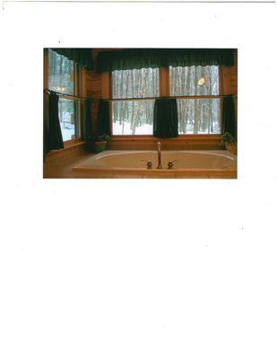 Custom bathroom with whirlpool tub and views of outside.