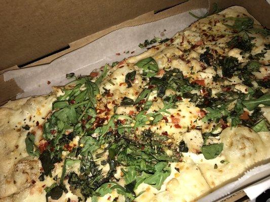 Chicken alfredo pizza with arugula, cilantro, basil, oregano, red pepper, and garlic oil. Yum!