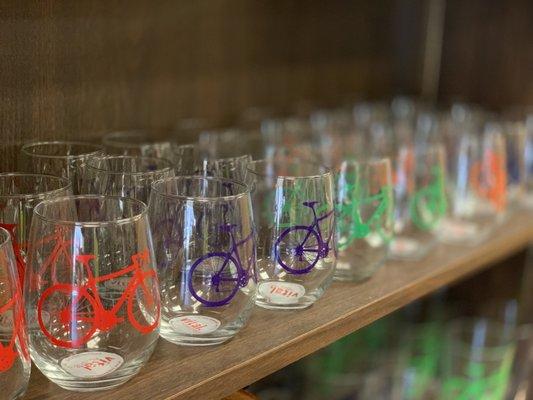 Bike-themed barware including stemless wine glasses, pint glasses, and bottle openers made of bike chains.