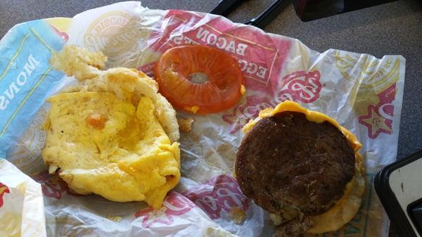 Mustard and tomatoes on a sausage, egg and cheese biscuit.