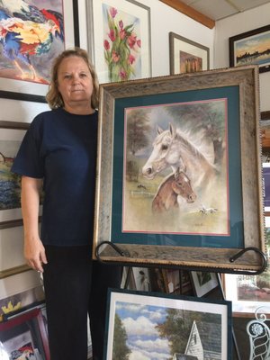 Store manager Sherry Brown displaying country art and frame.