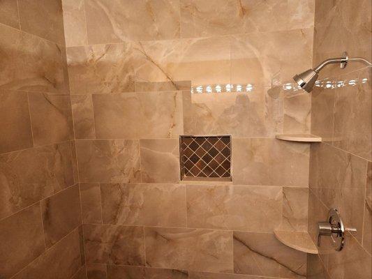 Custom tiled shower with lit soap dish.