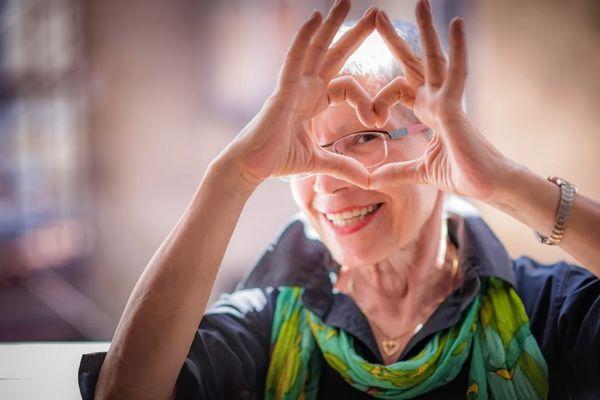 female senior making heart shape with her hands and smiling