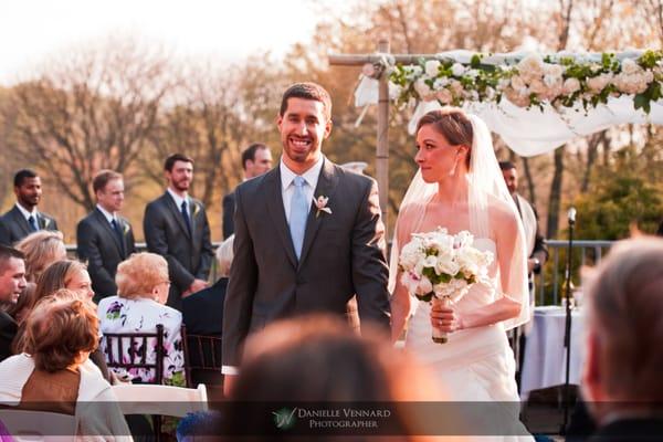 bride glancing at groom as they walk back up the aisle as husband and wife