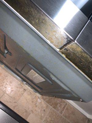 Grease build up on underside of microwave after two additional cleaning visits before move in