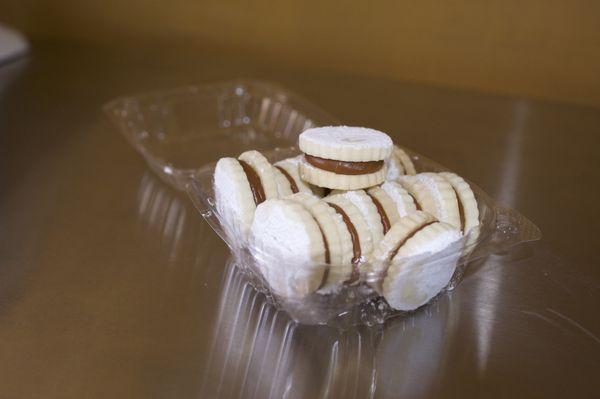 Delicious soft cookies filled with dulce de leche (caramel) and topped with a light coat of sweet powder sugar. (Contains: Milk, Wheat)