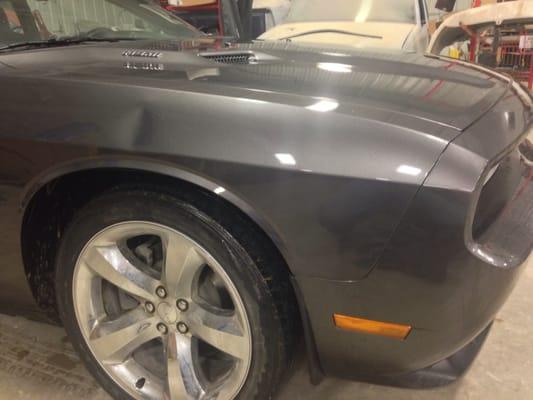 Softball size dent on the fender of a Dodge Challenger.