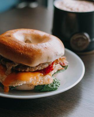 Sausage, egg, & cheese breakfast bagel, customized with bacon, peppers and spinach