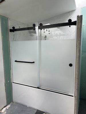 Double sliding tub shower door with starphire glass and matte white film applied on the exterior 41" up. All matte black finish.