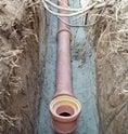 Clay Sewer Pipeline Installation in trench amidst other utilities and tree roots.