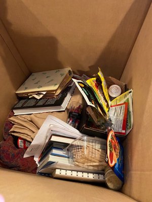 Spices (unwrapped and some still opened) placed in a box with books and tablecloths. Nothing wrapped and spiced spilled. What a mess.