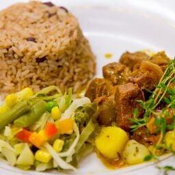 Curry goat with rice & peas and steamed vegetables.