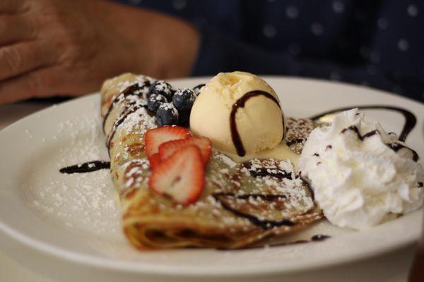 Strawberries and blueberries filled crepe with a vanilla ice cream on top