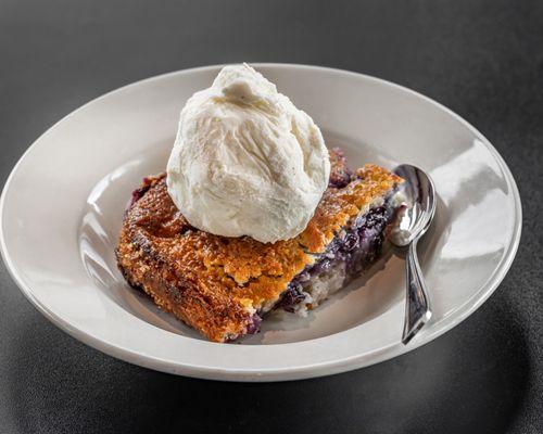 Cobbler made with seasonal fruit, including apples, blueberries, and peaches, topped with vanilla bean ice cream.