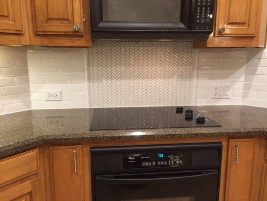 Backsplash with picture frame design above cooktop.