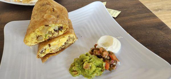 breakfast burrito served with guacamole,  salsa and sour cream