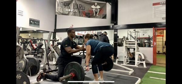 Teaching client proper form and technique for a standard deadlift.