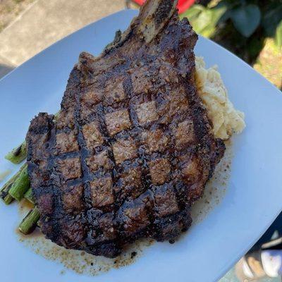 Grilled bone-in ribeye steak accompanied by asparagus and mashed potatoes