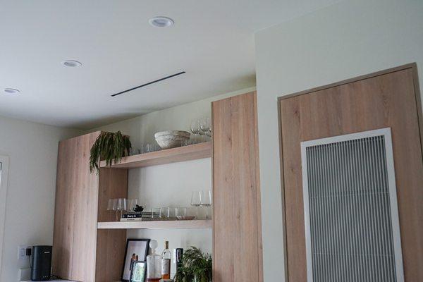 Linear diffuser above bar and modern return grill on A/C door.