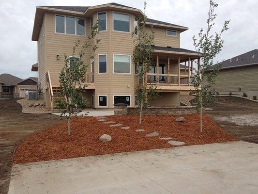 Shredded Red Cedar Mulch with natural flagstone steppers creates a unique planting area between hardscapes.