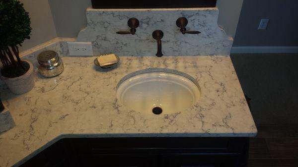 Under-mount sink with oil rubbed bronze wall mounted faucet.