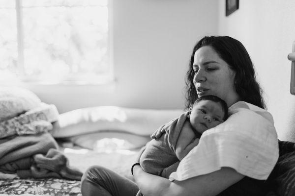 A mother holds her newborn baby at an in-home newborn photo session