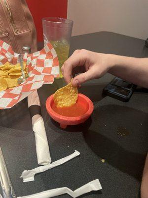 A chip about to lose it life battle in a bowl of fresh dipping salsa