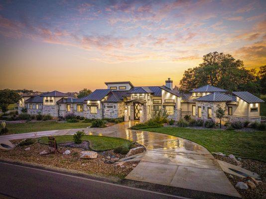 Front of the KC Custom Homes model home at sunset. Large semi-circular drive way with dramatic lighting. San Antonio Custom Home Builder