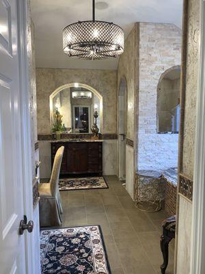 We added character to this primary bathroom by adding arches, stoned walls, & beautiful rugs & accessories