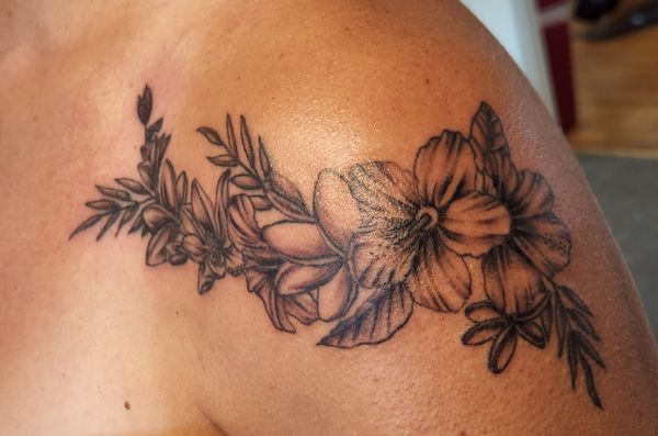 Black and gray floral tattoo wrapping from upper arm to collar bone