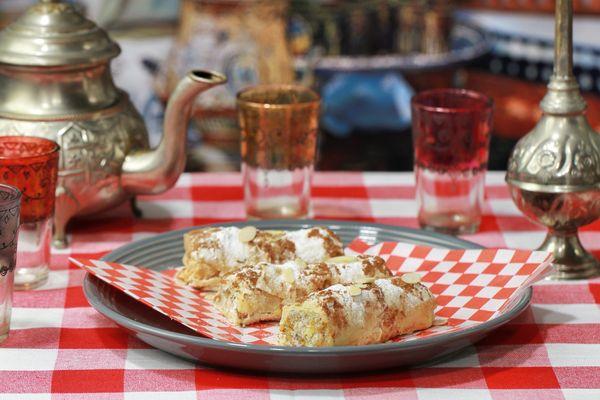 CHICKEN BASTILLA CIGARS:
 Baked layers of phyllo dough, stuffed stuffed w/ eggs, chicken, almonds, sprinkled with cinnamon & powdered sugar.