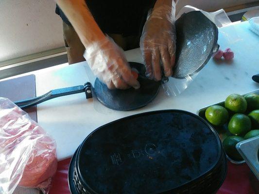 Hand presses each tortilla