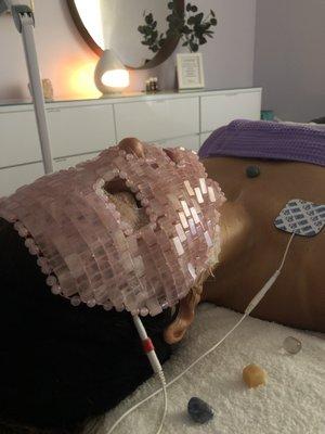 Client receiving lymphatic detox with TAMA microcurrent - TAMA facial therapy, and relaxing with quartz crystal mask.