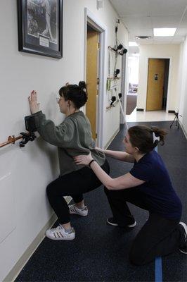 Assisting a patient with a front wall squat