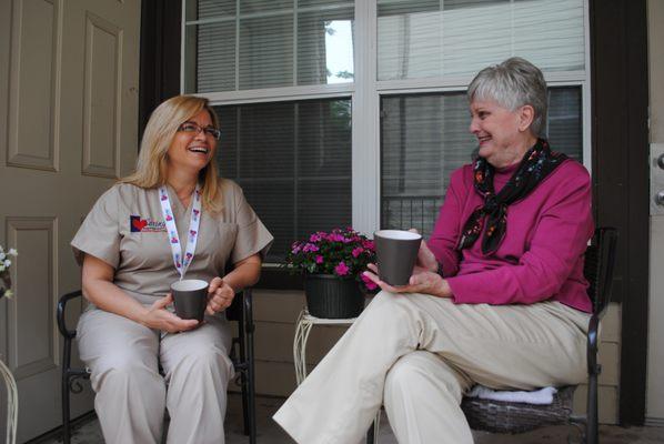 Caring Senior Service caregiver with a client drinking coffee on the porch