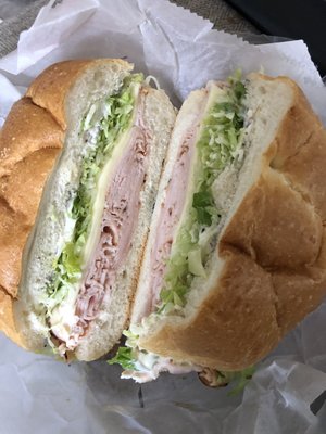 Honey turkey provolone lettuce red onion and mayonnaise on a round roll.