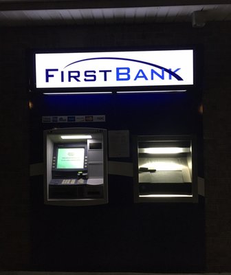 ATM at night outside building, directly on sidewalk (not enclosed)