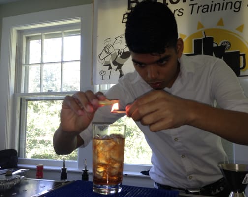 Brian is flaming an orange at Bartenders Inc. Workshop!