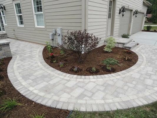 A curved brick walkway that connects the side door to the rear patio.