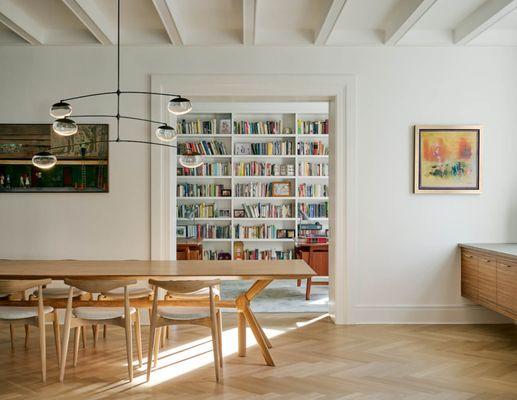 A new beamed ceiling clarifies the dining room in the apartment with a view to the library beyond.