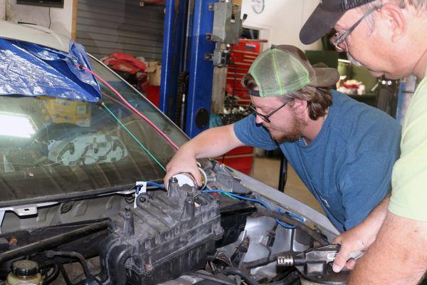 Student installing Transmission Fluid on one of several project vehicles.