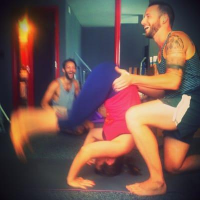 Joseph assists a student into headstand.