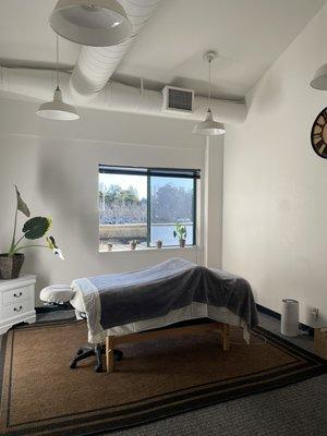 BodyWorks By Rae's indoor healing space with HEPA air filter, open window, and high ceiling.