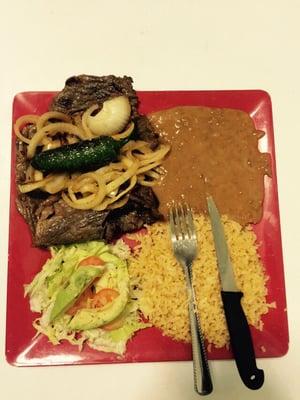 Plate of carne Asada with fried onions and rice beans and  hand made tortillas