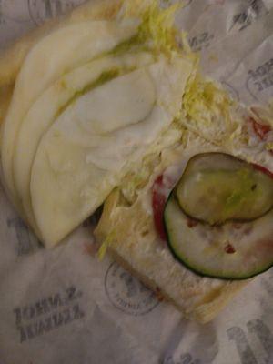 11-21-23. Two slices of cheese folded in half to look like more, two pickles, lettuce and avocado spread peeking out.