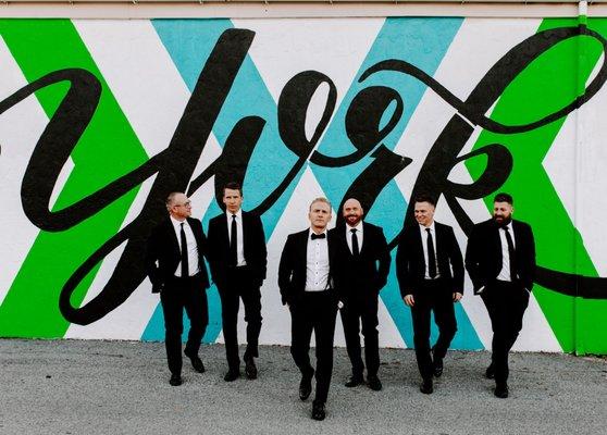 Groom and groomsmen's stylish photo with one of many murals in Royal Square.