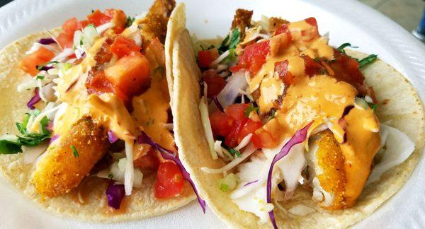 Fish Tacos  beer batter fish, on a corn tortilla, filled with cilantro, onion, cabbage, tomato, chipotle sauce and a lemon wedge.