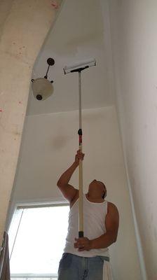 Ismael painting a high ceiling