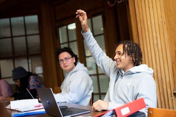 High School student raising hand in small classroom.