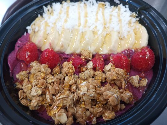 Make your own Acai bowl with Protein Granola, banana, raspberry, and coconut shavings